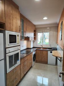 una cocina con armarios de madera y electrodomésticos blancos en Atenas 2 - Monty´s, en Jávea