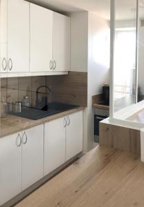 una cocina con armarios blancos y fregadero en F2 cosy central I Rueil-Malmaison I La BonBonniere 92500, en Rueil-Malmaison