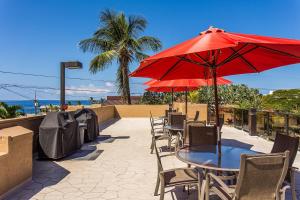 a table and chairs with a red umbrella on a patio at Kona Pacific C319 in Kailua-Kona