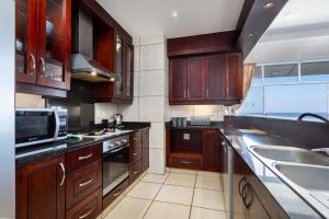 a kitchen with wooden cabinets and a sink and a microwave at Colonial Sands 403 in Margate