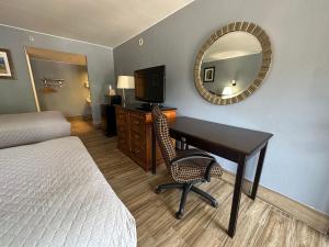a hotel room with a desk and a bed and a mirror at HillView Inn at Six Flags Fiesta in San Antonio