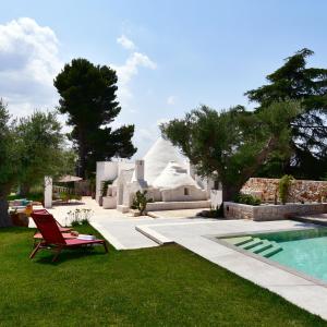 un patio con una silla y una piscina en IL TRULLO BIANCO - Country House & SPA, en Castellana Grotte