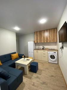 a living room with a blue couch and a kitchen at Under the forest in Kazbegi