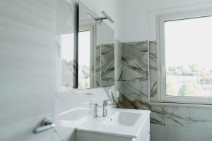 La salle de bains blanche est pourvue d'un lavabo et d'un miroir. dans l'établissement CASALMARE, à Casalbordino