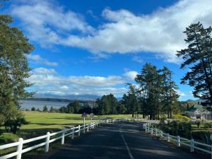 una carretera que conduce a un campo de golf con una valla blanca en The Lake House - Theewaterskloof Golf Estate en Villiersdorp