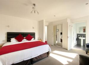 a bedroom with a large bed with red pillows at Rosebank Guest House in Perth