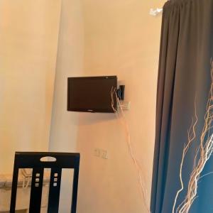 a tv on a wall with a chair and a curtain at Hotel & Resort Lunatenuta in Mondragone