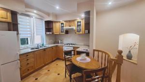 a kitchen with a wooden table and a kitchen with a refrigerator at Apartamenty Nadbrzeżna Premium 2 in Augustów