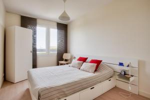 Un dormitorio blanco con una cama grande con almohadas rojas en Escapade sur l'île de Nantes avec vue sur la Loire en Nantes