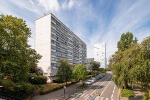 un edificio blanco alto junto a una calle con coches en Escapade sur l'île de Nantes avec vue sur la Loire en Nantes