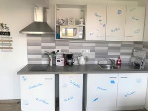a kitchen with white cabinets and a counter top at LA MAISON DU BONHEUR in Rochefort