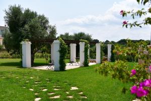un jardín con pérgola, sillas y flores en IL TRULLO BIANCO - Country House & SPA, en Castellana Grotte