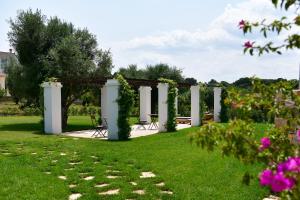 a garden with a pergola and chairs and flowers at IL TRULLO BIANCO - Country House & SPA in Castellana Grotte