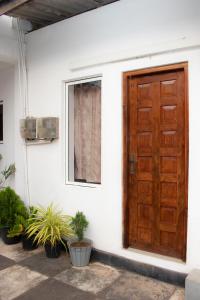 a wooden door on the side of a house with plants at Mount Guest in Karagampitiya