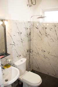 a white bathroom with a toilet and a sink at Mount Guest in Karagampitiya