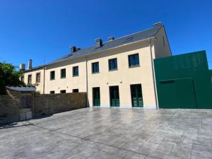 a large white building with green doors and a sky at O TEU SITIO in Ribadeo