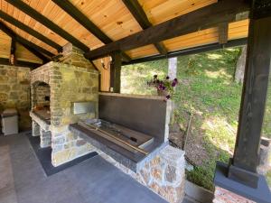 an outdoor patio with a stone fireplace with a wooden ceiling at Vikendica Bella in Bihać