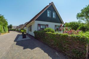 una casa con techo verde y valla en Buitenplaats 62 Callantsoog, en Callantsoog
