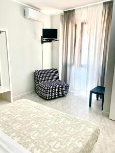 1 dormitorio con 1 cama, 1 silla y TV en Le 4 Stagioni rooms, en Francavilla al Mare