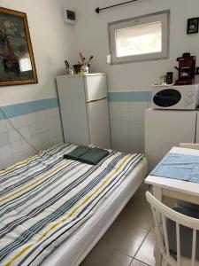 Habitación pequeña con cama y nevera. en SunShine Apartman, en Orfű