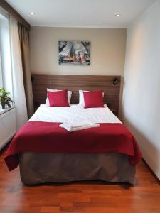 a bedroom with a large bed with red pillows at Gamleby Hotell in Gamleby