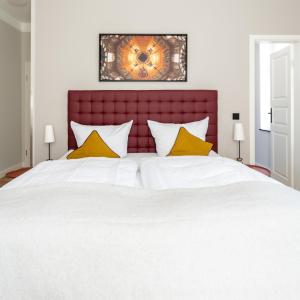ein Schlafzimmer mit einem großen weißen Bett mit gelben Kissen in der Unterkunft Up Hus Hotel Neuruppin in Neuruppin