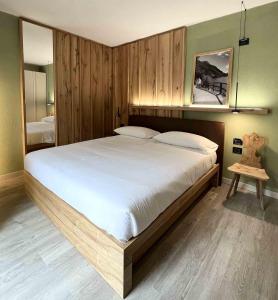 Schlafzimmer mit einem großen Bett und Holzwänden in der Unterkunft Albergo Dimaro Wellness Hotel in Dimaro