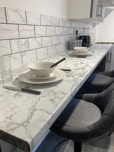 a kitchen with a marble counter top with bowls and chairs at Apartment 8 - Luxury Living & free parking in Nottingham