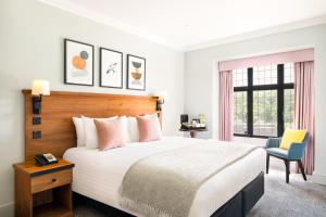1 dormitorio con 1 cama grande y 1 silla en voco Lythe Hill Hotel & Spa, an IHG Hotel, en Haslemere