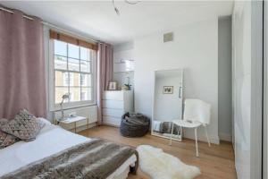 1 dormitorio con cama blanca y ventana en Stylish 2 FLOOR 2BED house 1 MIN walk to Camden station! FREE PARKING! en Londres
