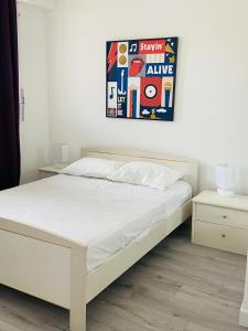 ein Schlafzimmer mit einem weißen Bett mit einem Bild an der Wand in der Unterkunft Très bel appartement sur la plage avec grande terrace face à la mer! La Goelette in Vallauris