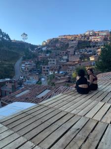 Due persone sedute su un tetto che guardano una città di Balcón de Qenqo a Cuzco