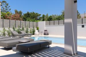 een zwembad met ligstoelen en een zwembad bij Monti Luxury Villa, Close to South Crete beaches, By ThinkVilla in Lefkogeia