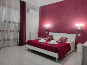 um quarto com uma cama com uma parede vermelha em La casa di Anna em Villabate