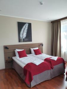 a bedroom with a large bed with red pillows at Gamleby Hotell in Gamleby
