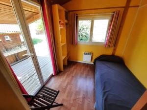 um pequeno quarto com uma cama e uma janela em Résidence Les Chalets de Millau em Millau