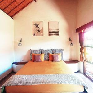 um quarto com uma cama grande e almofadas laranja em Classico Italiano em Gili Air