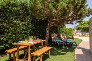 een houten tafel en banken onder een boom bij Villa Calan Brut 51 in Cala en Blanes