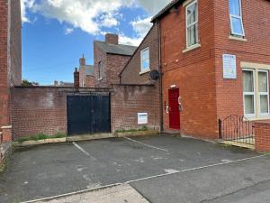 un aparcamiento vacío frente a un edificio de ladrillo en Flat 1 Petteril House, en Carlisle