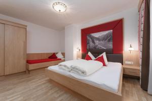 Schlafzimmer mit einem weißen Bett mit roten Akzenten in der Unterkunft Appartement Oskar in Sölden