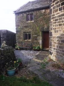 a brick building with a door and a yard at Knoll Top Cottage in Todmorden