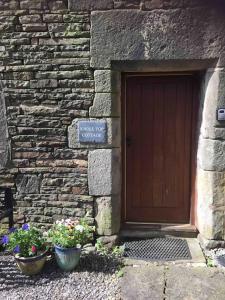 a stone building with a wooden door and two pots of flowers at Knoll Top Cottage in Todmorden