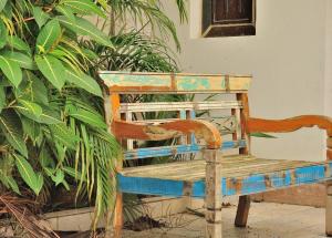 an old wooden bench sitting in front of plants at Bertioga Beach Hostel in Bertioga