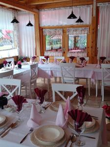 une salle à manger avec des tables et des chaises blanches avec des serviettes roses dans l'établissement Penzion Valerija, à Zgornje Jezersko