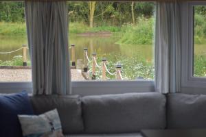 a living room with a view of a lake through a window at Lapwing Lodge in Louth