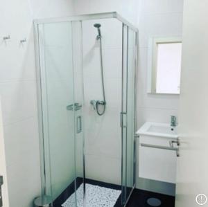 uma cabina de duche em vidro na casa de banho com um lavatório em Casa da Vila Guest House na Póvoa do Varzim