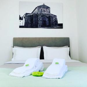 a bed with white towels and a black and white building at Casa da Vila Guest House in Póvoa de Varzim