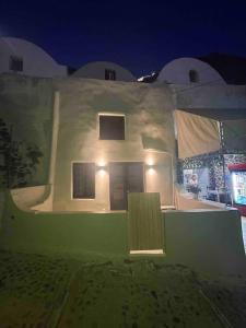 a white house with lights on it at night at Phaedra and Ariadni - Caldera Sea and Volcano Sea View 2 joined Houses in the Old Port of Fira, Santorini 4br-2ba-2livingr in Fira