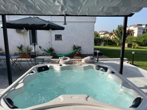 a hot tub on a patio with an umbrella at La Petite Famille in Corchiano