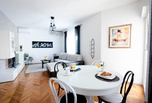 Apartman Karla في سيني: غرفة معيشة بيضاء مع طاولة وكراسي بيضاء